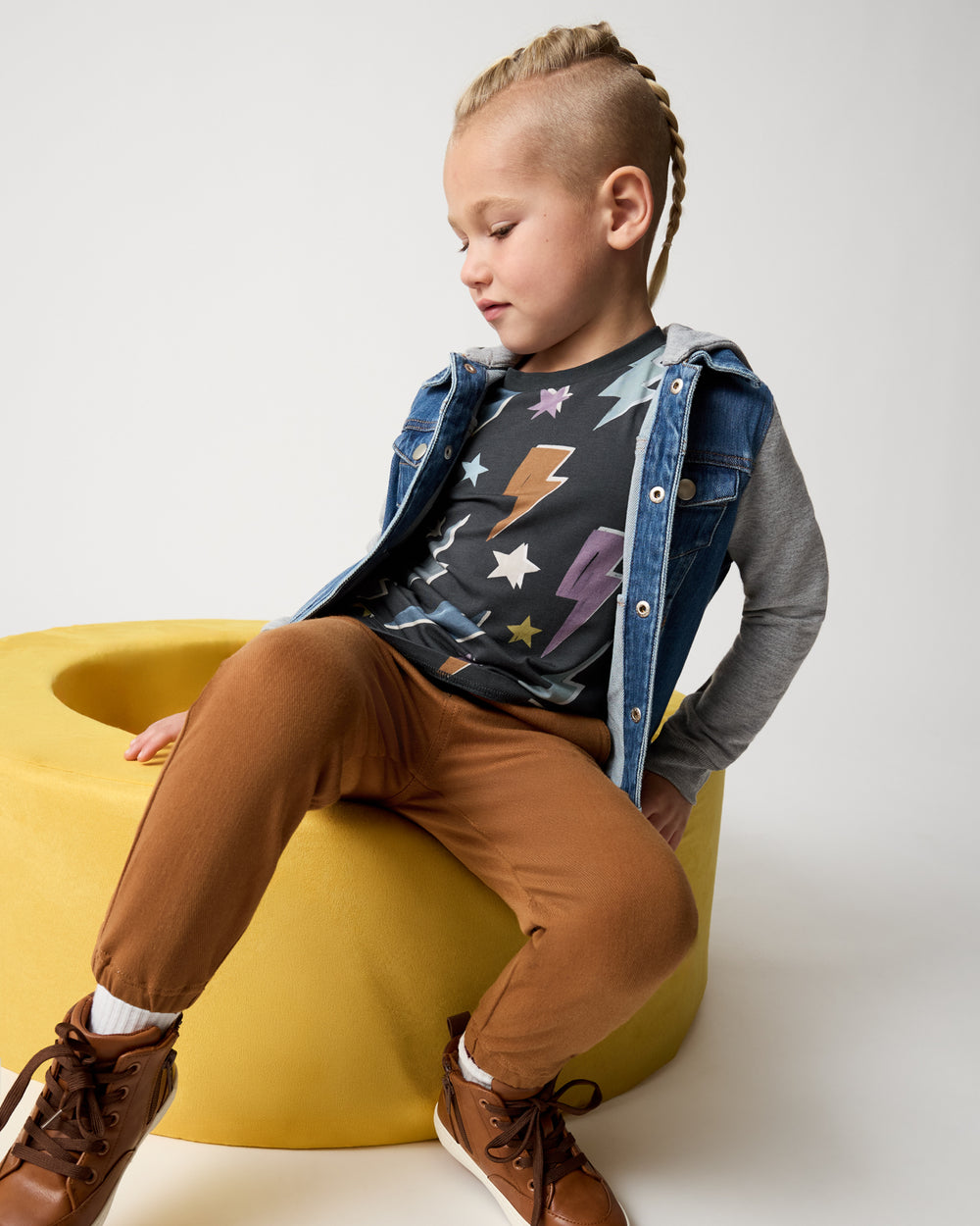 Boy wearing the Rich Toffee Denim Jogger on a yellow ottoman