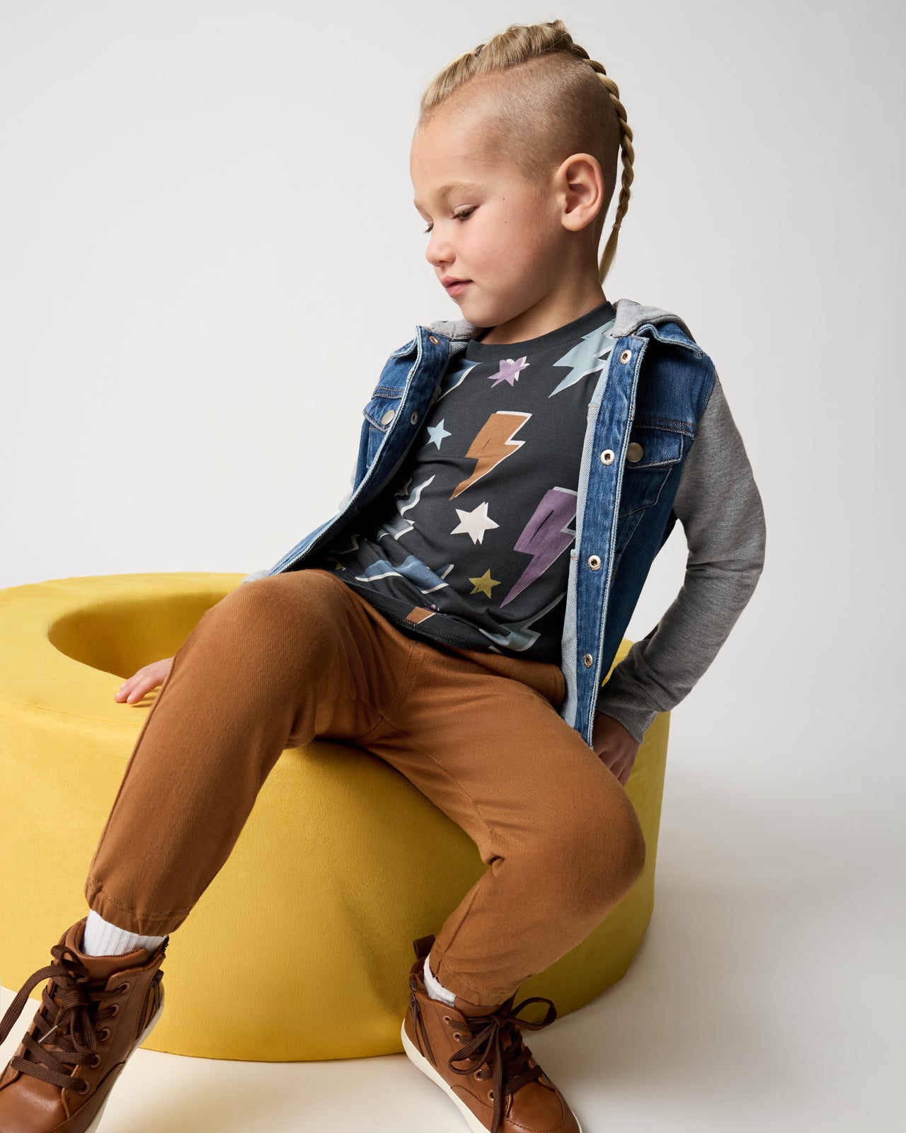 Boy wearing the Rich Toffee Denim Jogger on a yellow ottoman