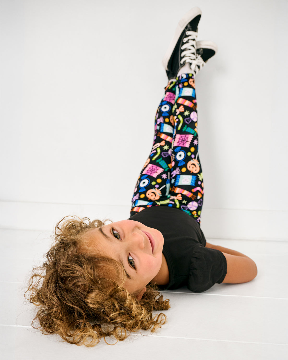 Child wearing the Halloween Haul Legging laying with her legs rested against the wall