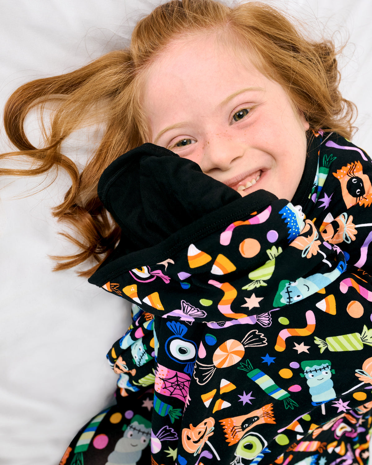 Laying child wrapped in the Halloween Haul Large Cloud Blanket®