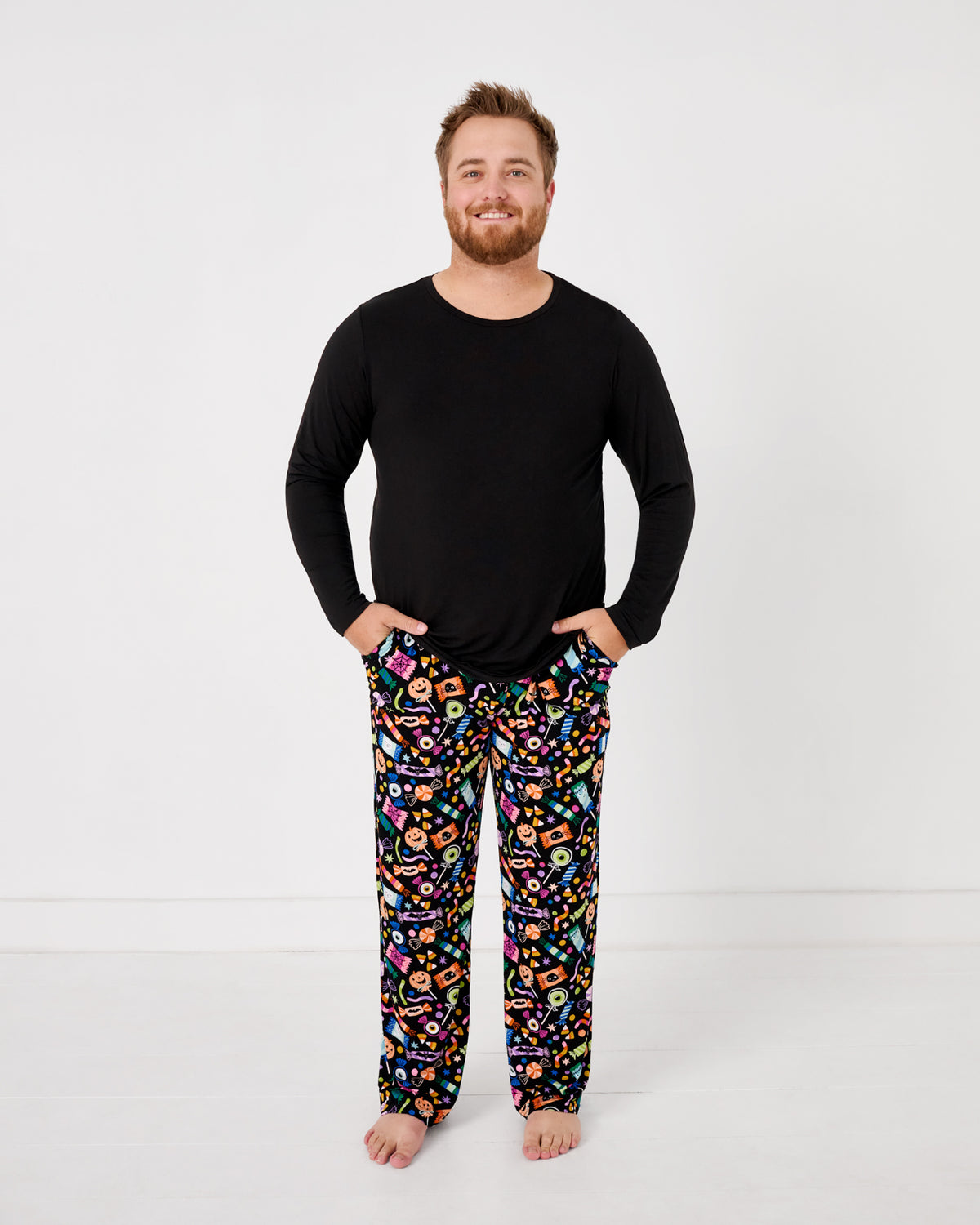 Standing man wearing the Halloween Haul Men's Pajama Pants with a black mens pajama top