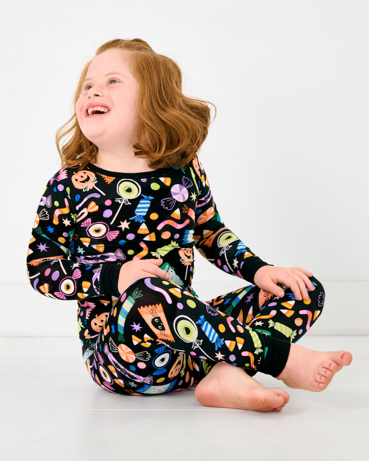 Sitting girl wearing the Halloween Haul Two-Piece Pajama Set