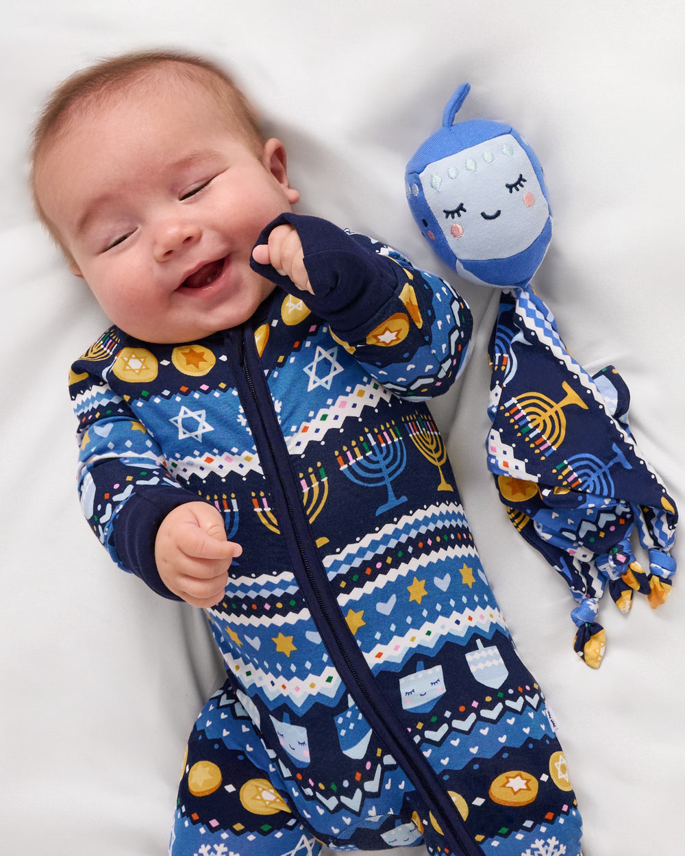 Baby laying with the Danny the Dreidel Sleepyhead Lovey