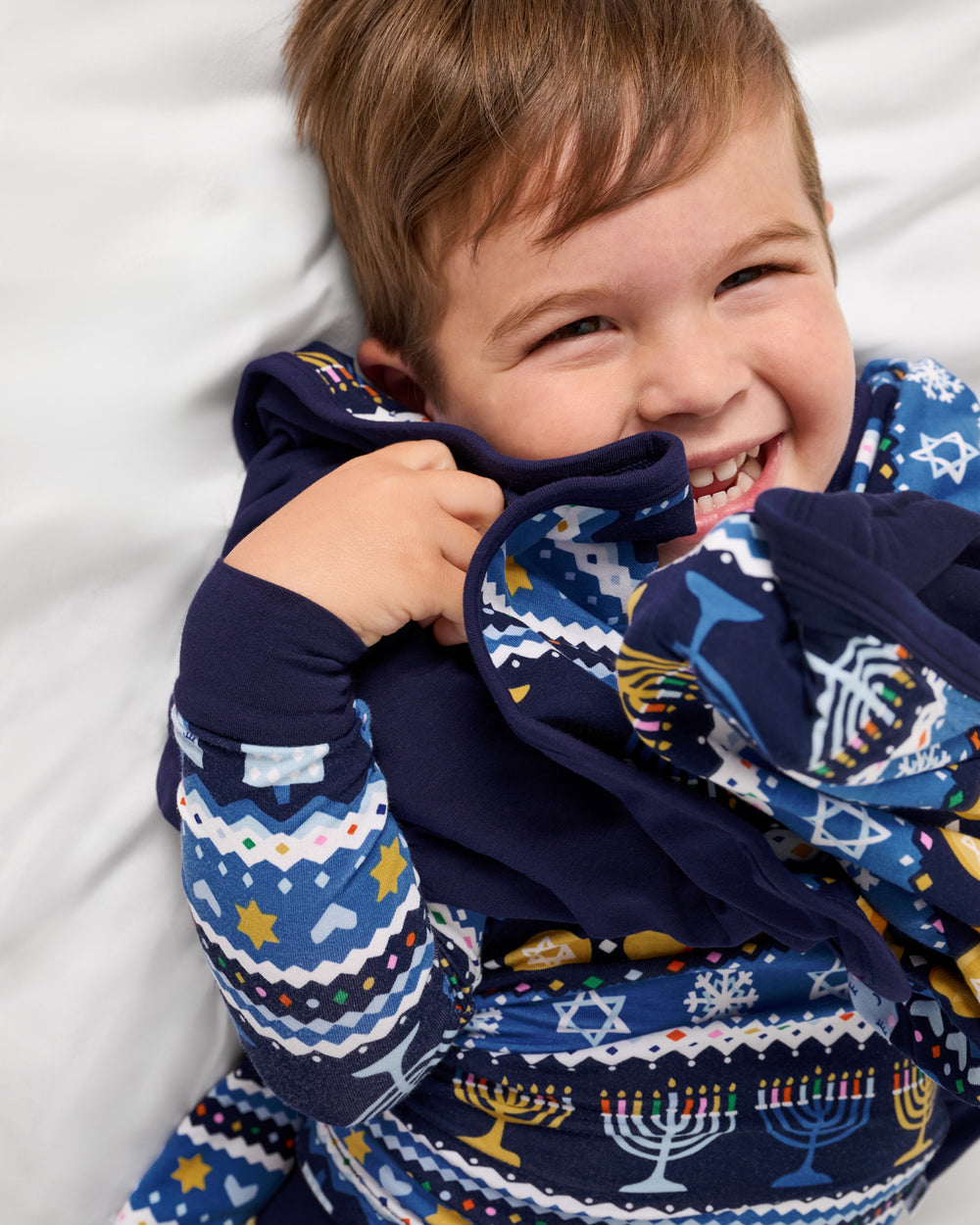 Close up of boy wrapped in the Hanukkah Fair Isle Large Cloud Blanket®