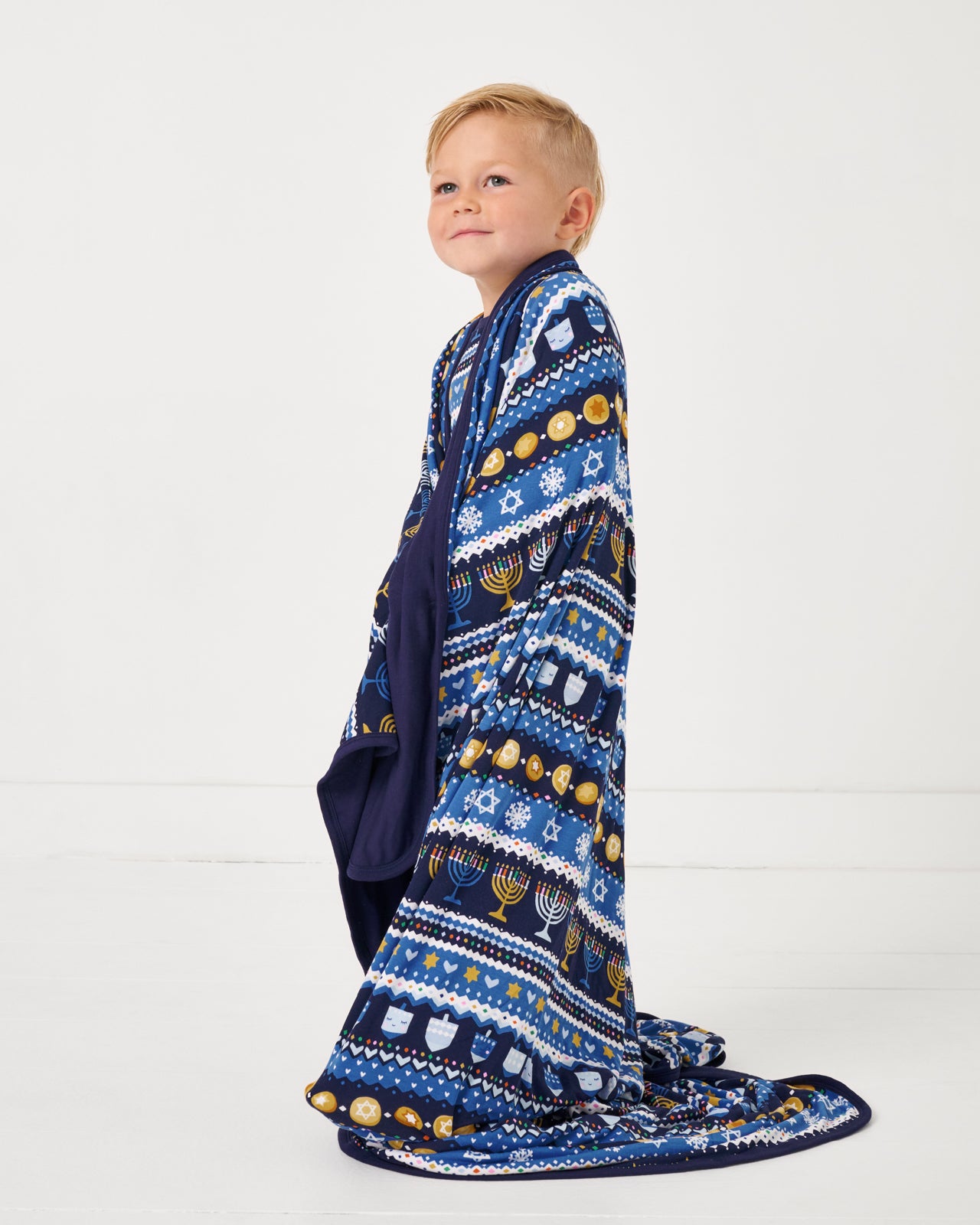 Boy wrapped in the Hanukkah Fair Isle Large Cloud Blanket®