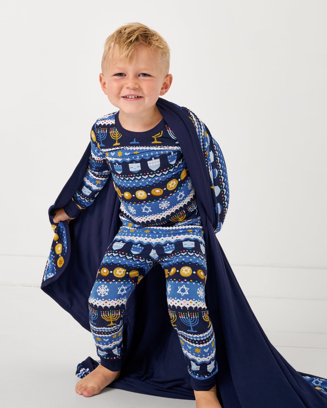 Boy wearing the Hanukkah Fair Isle Pajamas wrapped in the matching Large Cloud Blanket®