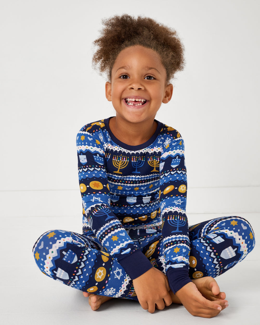 Sitting girl wearing the Hanukkah Fair Isle Two-Piece Pajama Set
