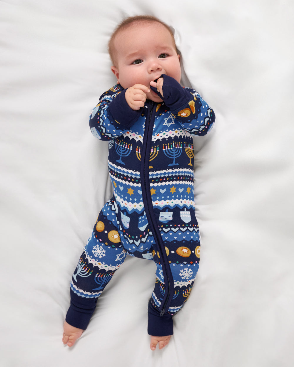 Aerial view of baby wearing the Hanukkah Fair Isle bamboo zipper pajamas