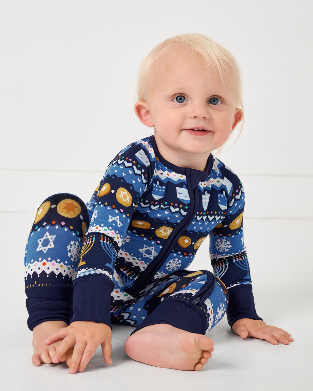 Sitting baby wearing the Hanukkah Fair Isle Zippy