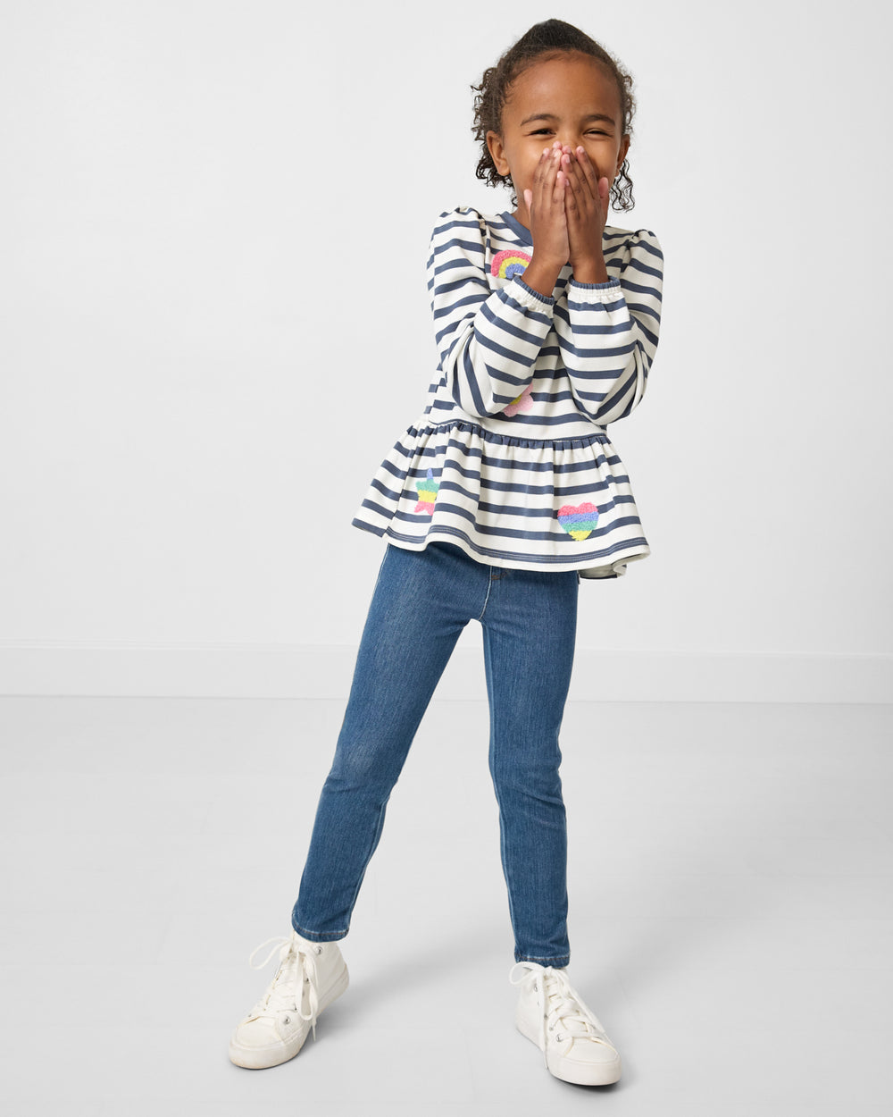 Child wearing the Hazy Blue Stripe Puff Sleeve Peplum Top with denim jeggings