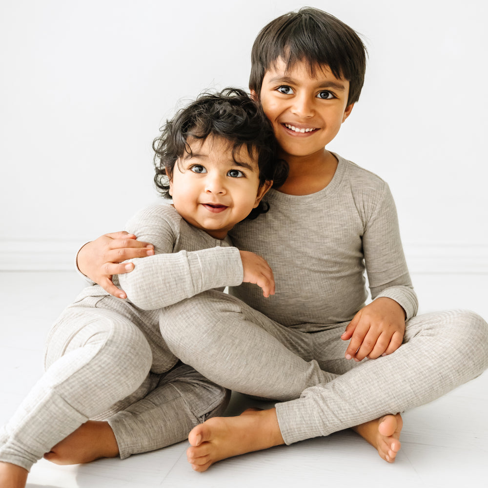 Click to see full screen - two siblings hugging wearing matching Heather Stone Ribbed pajamas in two piece and zippy styles