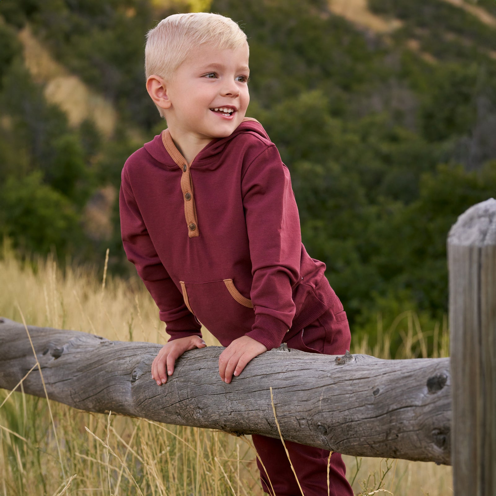 Close up image of boy outdoors while wearing the Classic Burgundy Henley Hoodie and Classic Burgundy Denim Joggers