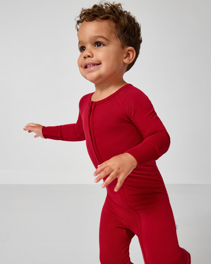 Child wearing a red onesie against a plain background