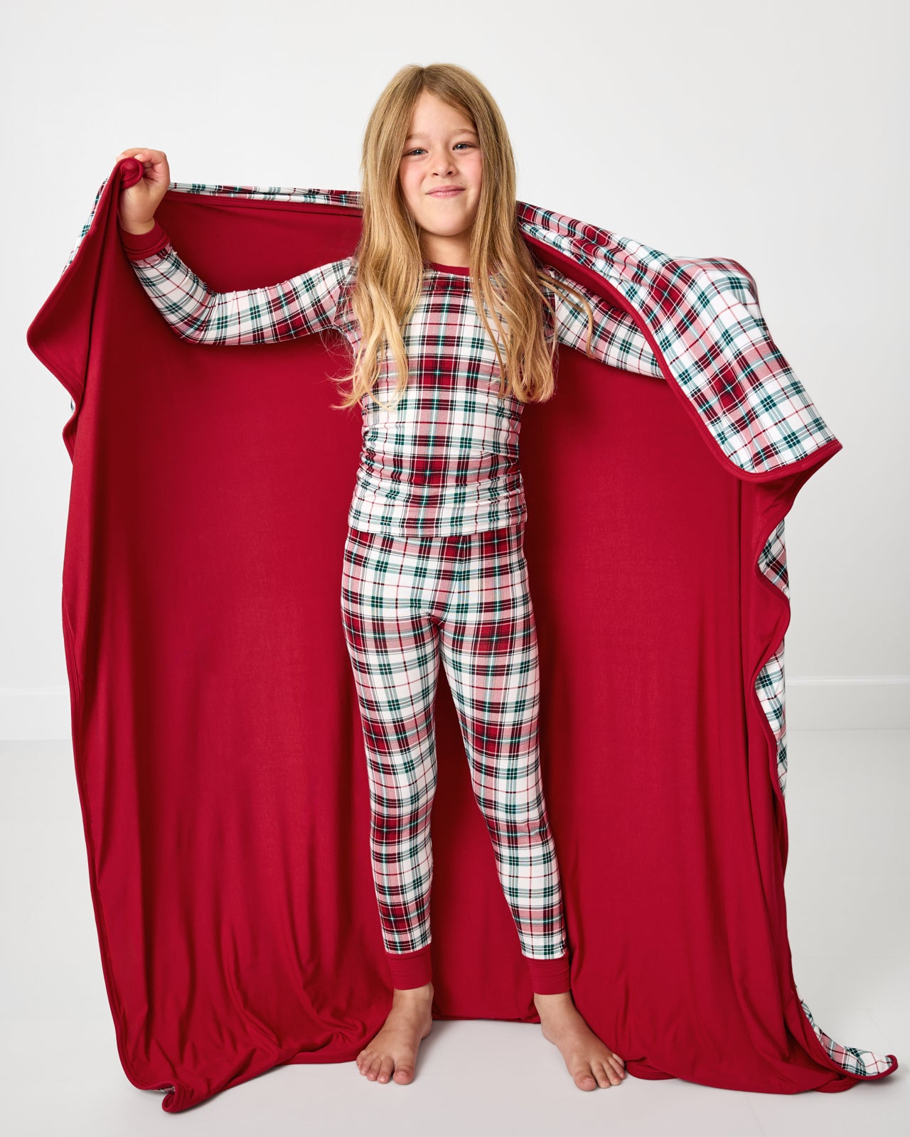 Child holding up the Holly Plaid Large Cloud Blanket® showing the solid red side