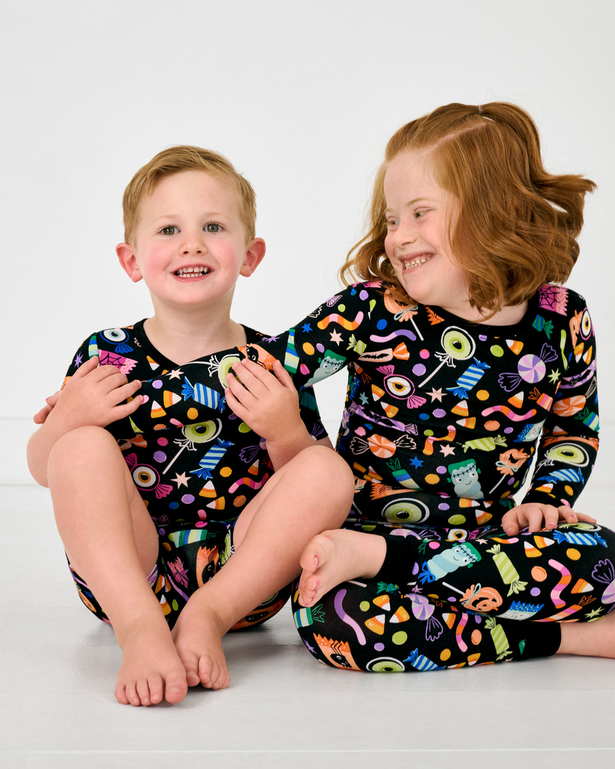 Two children wearing matching Halloween Haul Two-Piece Bamboo Pajama Sets