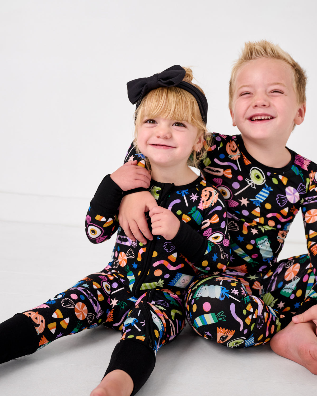 Two siblings wearing matching Halloween Haul halloween themed pajamas