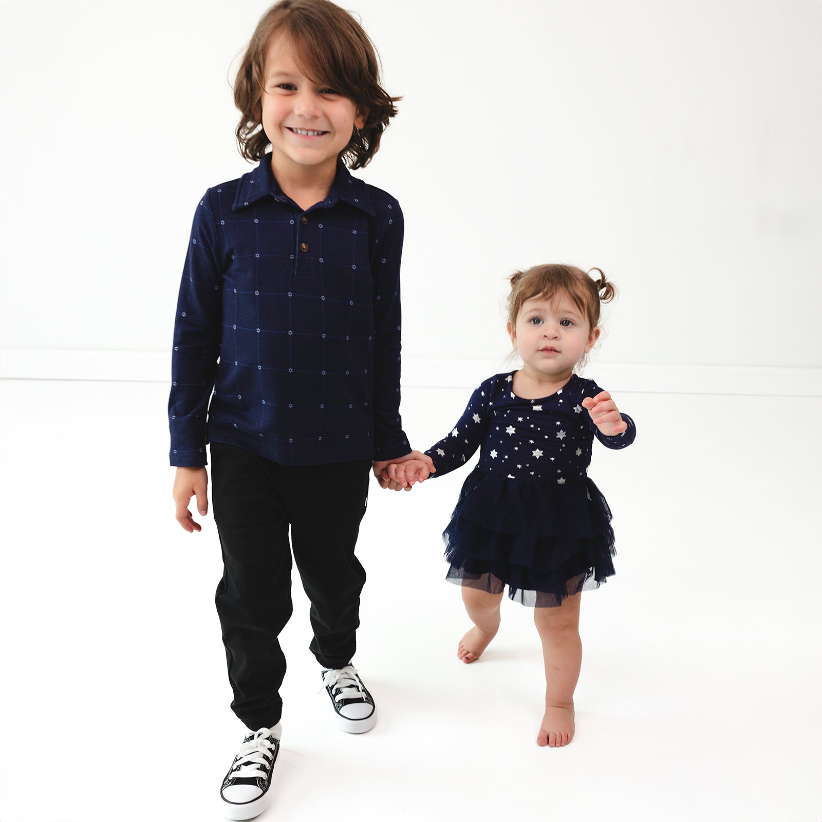 Two children holding hands wearing coordinating Hanukkah Stars Play outfits