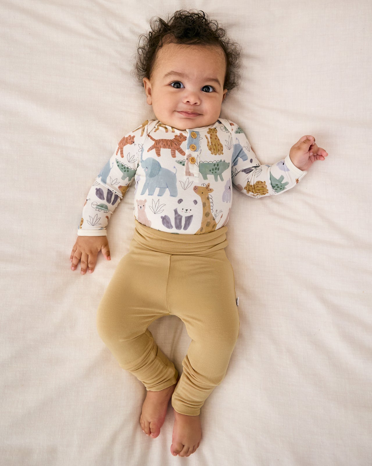 Aerial view of baby wearing the Hazel Wood Fold-Over Legging with a safari animal themed bodysuit