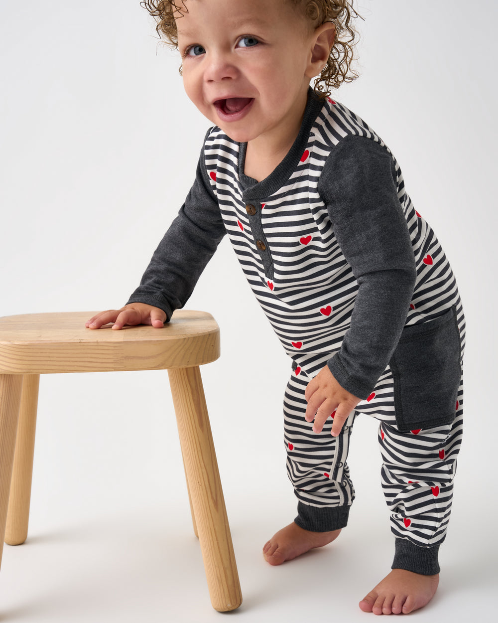 Walking toddler wearing the Heartstrings Stripe Henley Romper