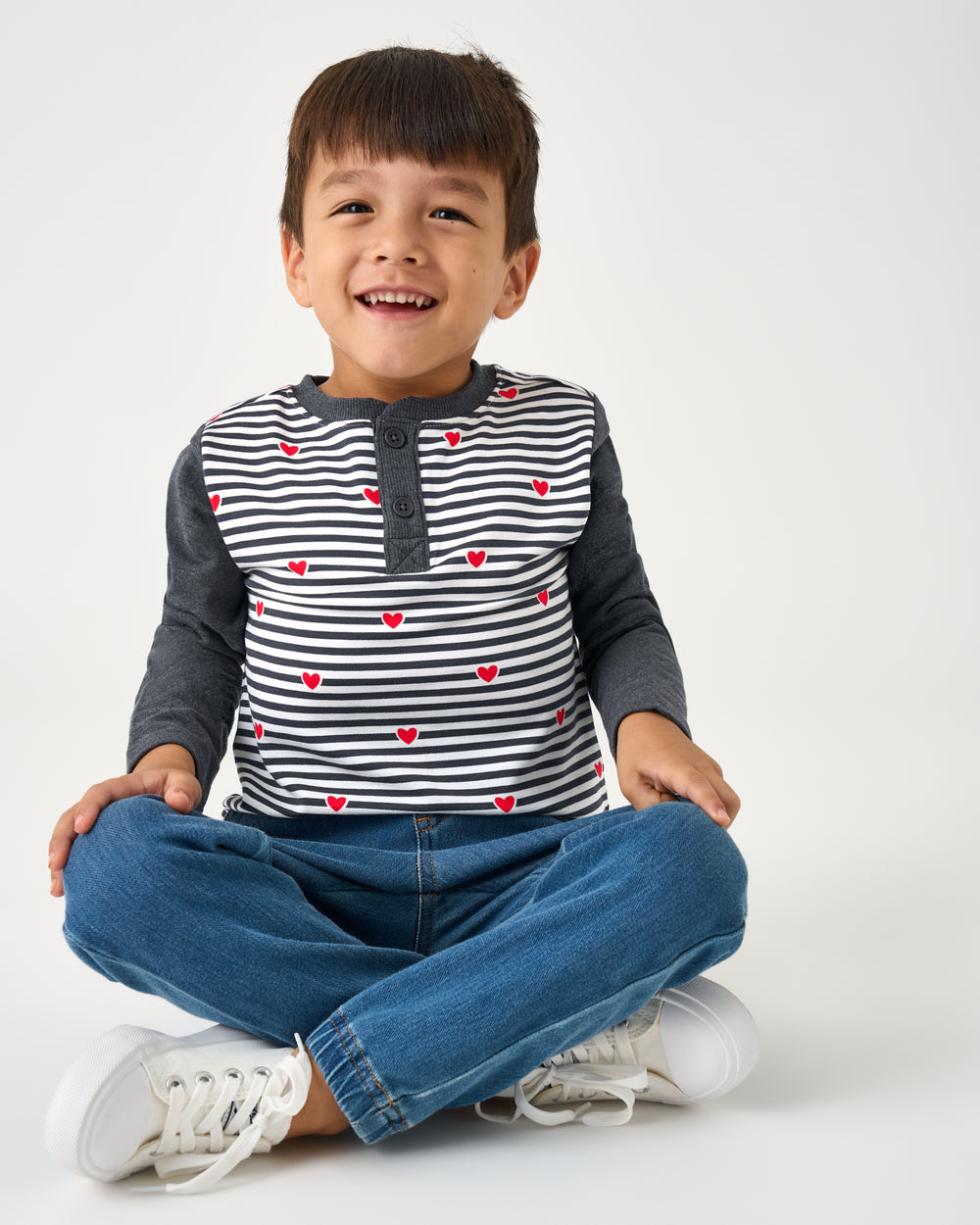 Sitting child wearing the Heartstrings Stripe Henley Tee