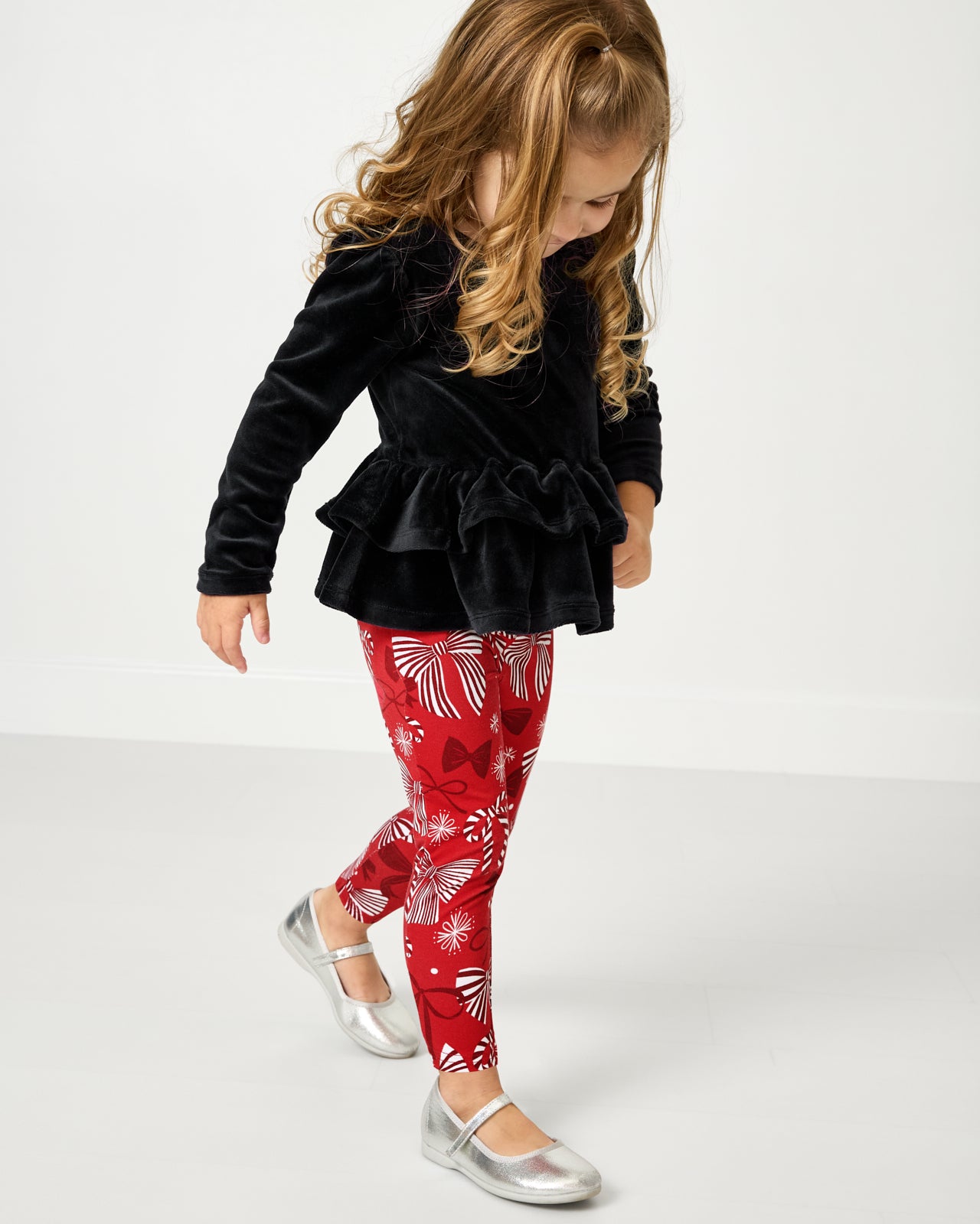 Girl wearing the Holiday Bows Legging with a Velvet Peplum Top