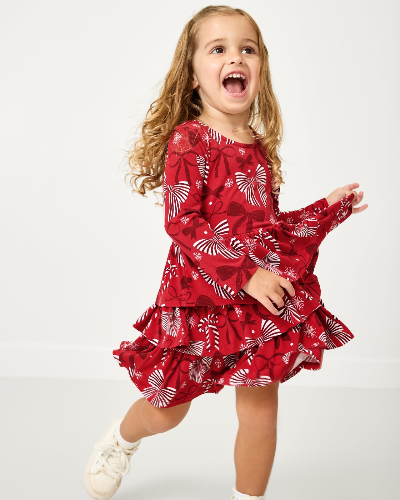 Walking child wearing the Holiday Bows Tiered Dress