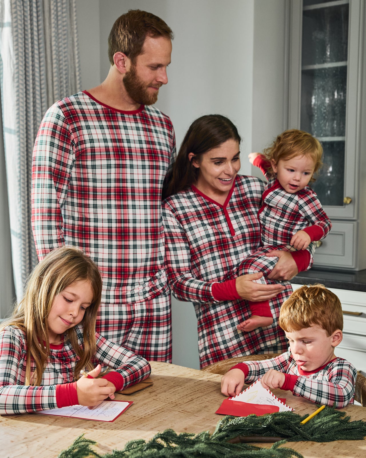 Family of five wearing Holly Plaid pajamas writing letters to Santa