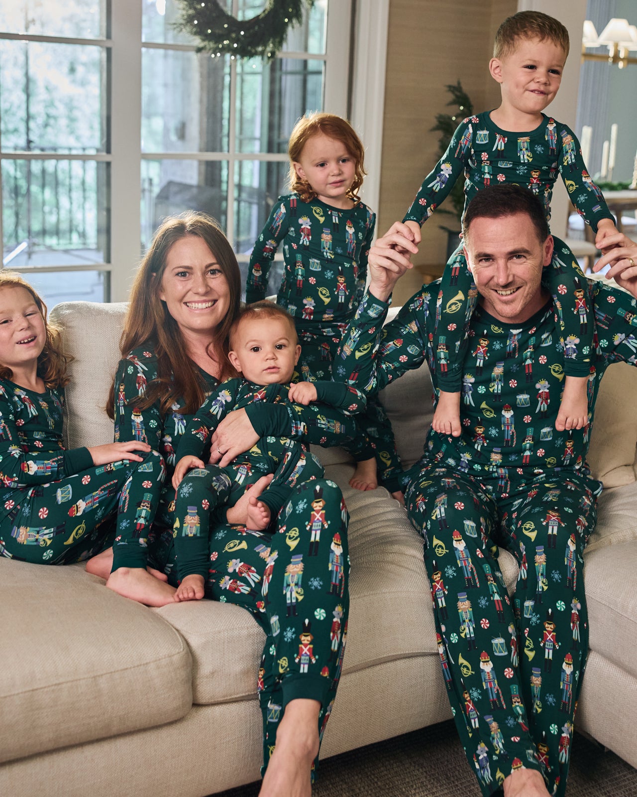 Family of six sitting on a couch wearing matching Nutcracker March pajamas