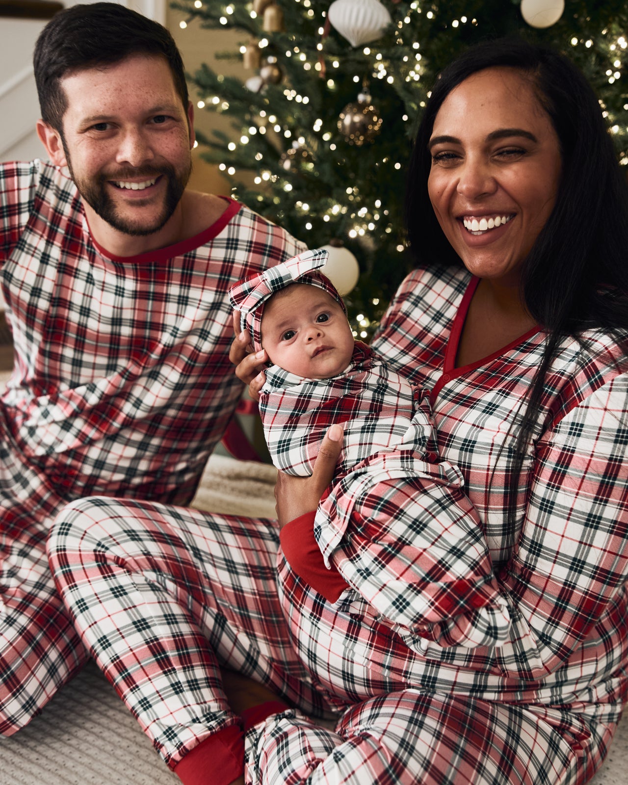 Mother holding baby wearing the Holly Plaid Swaddle & Luxe Bow Headband Set