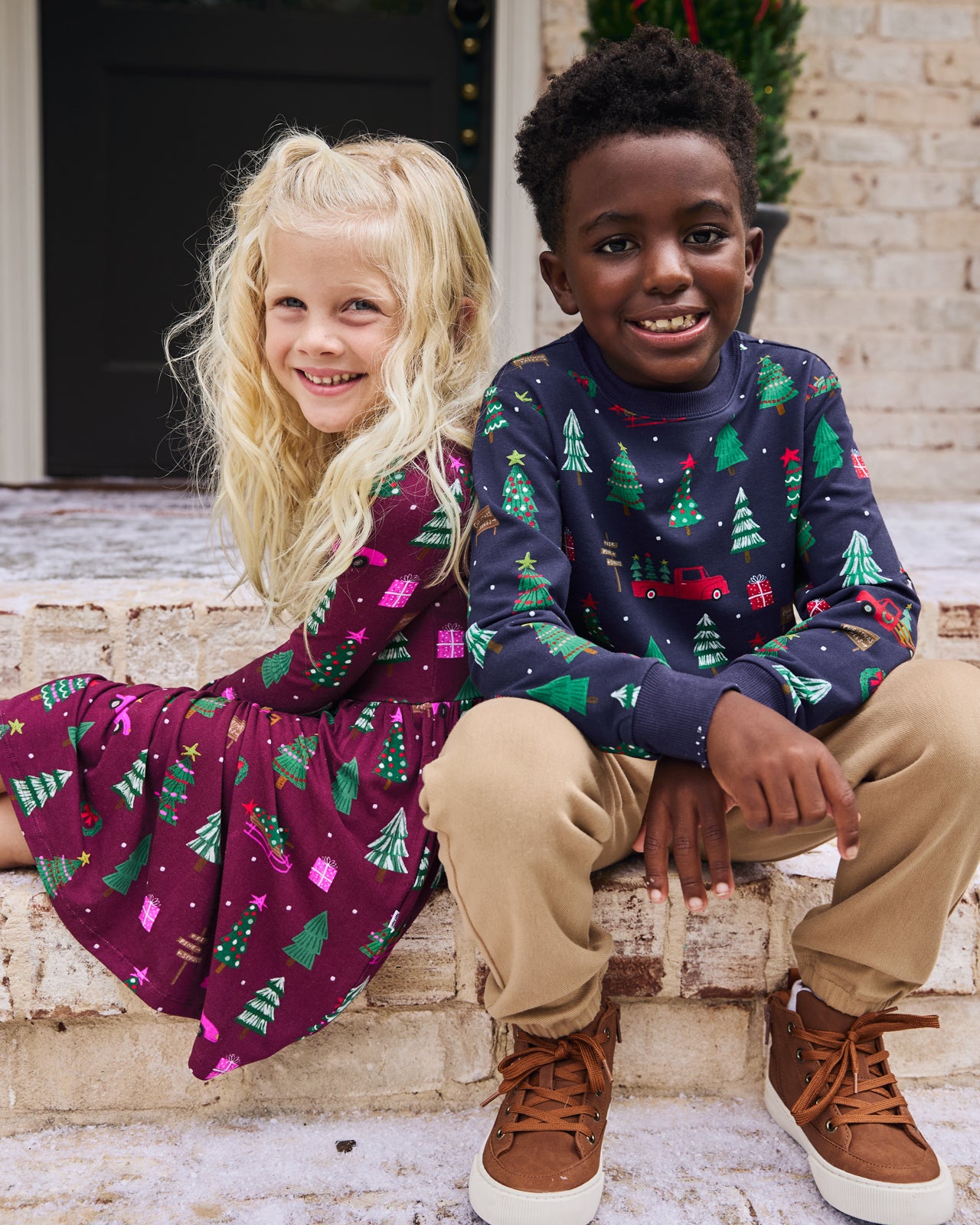Two kids on the front steps wearing matching Tree Traffic print styles