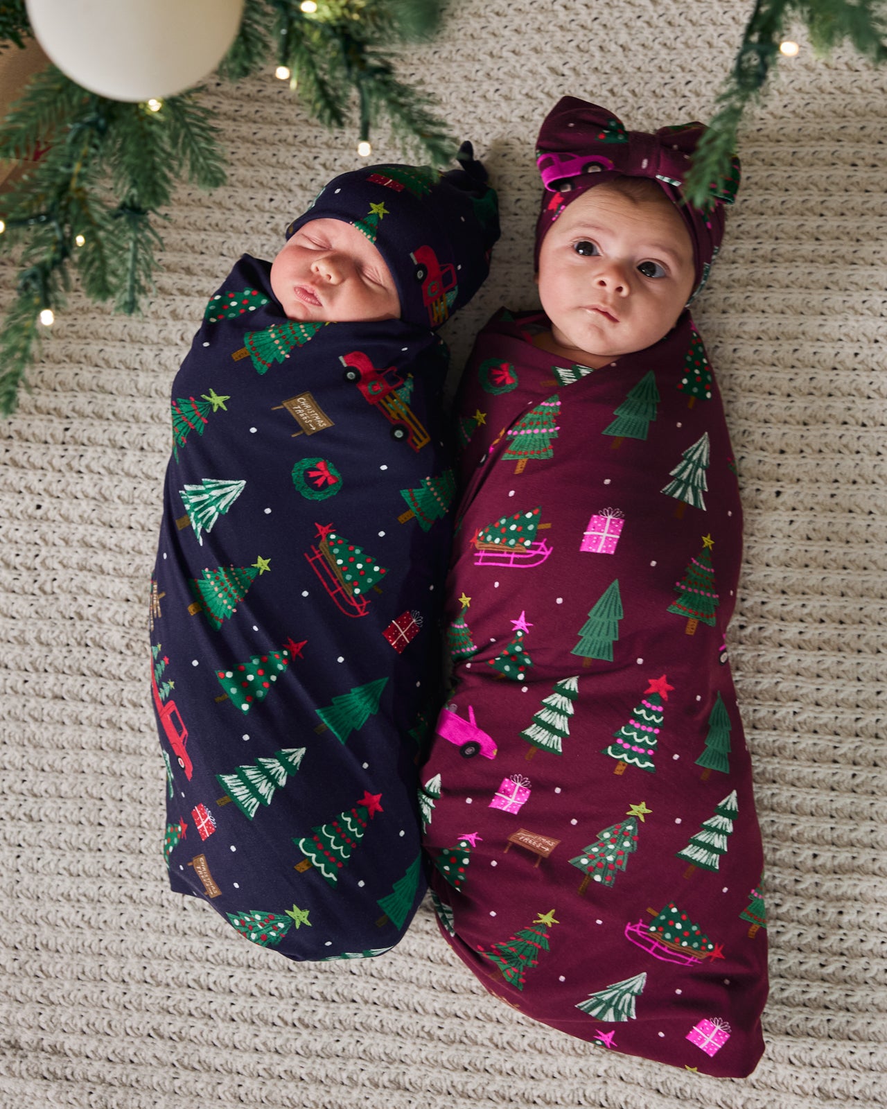Overhead view of two babies wearing Tree Traffic Swaddle Sets