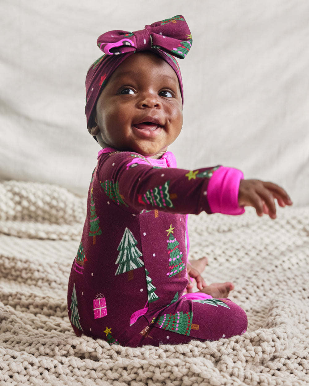 Baby sitting on a knit blanket wearing the Cranberry Tree Traffic Luxe Bow Headband