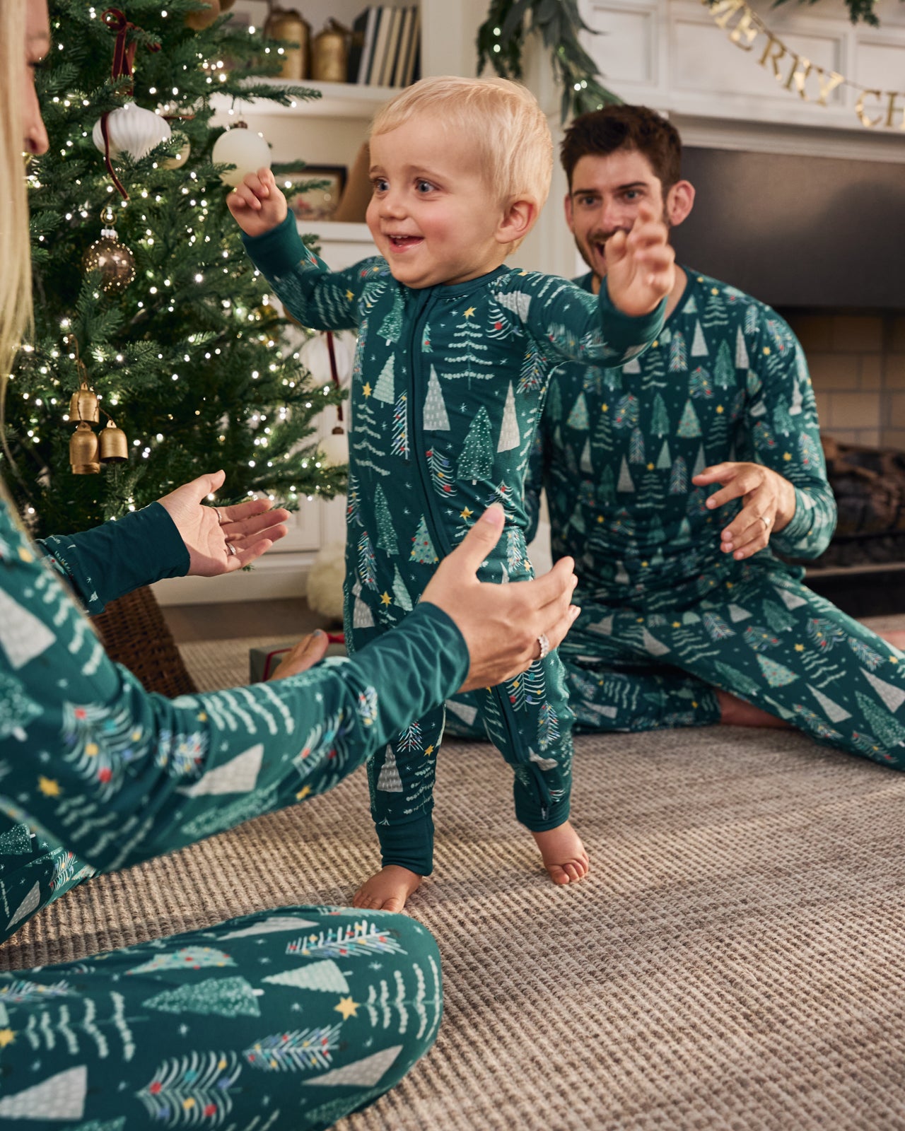 Family in a holiday themed living room wearing matching Twinkling Trees pajamas