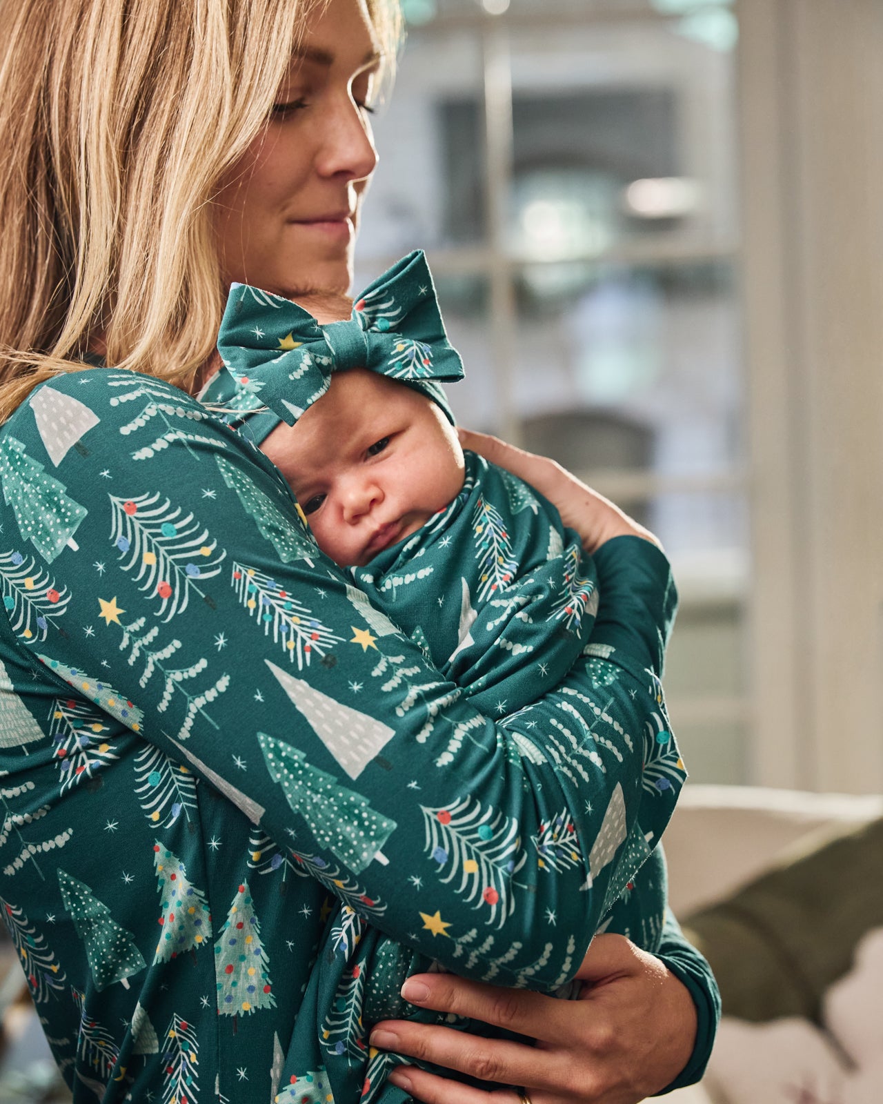 Mother holding baby wearing the Twinkling Trees Swaddle & Luxe Bow Headband Set