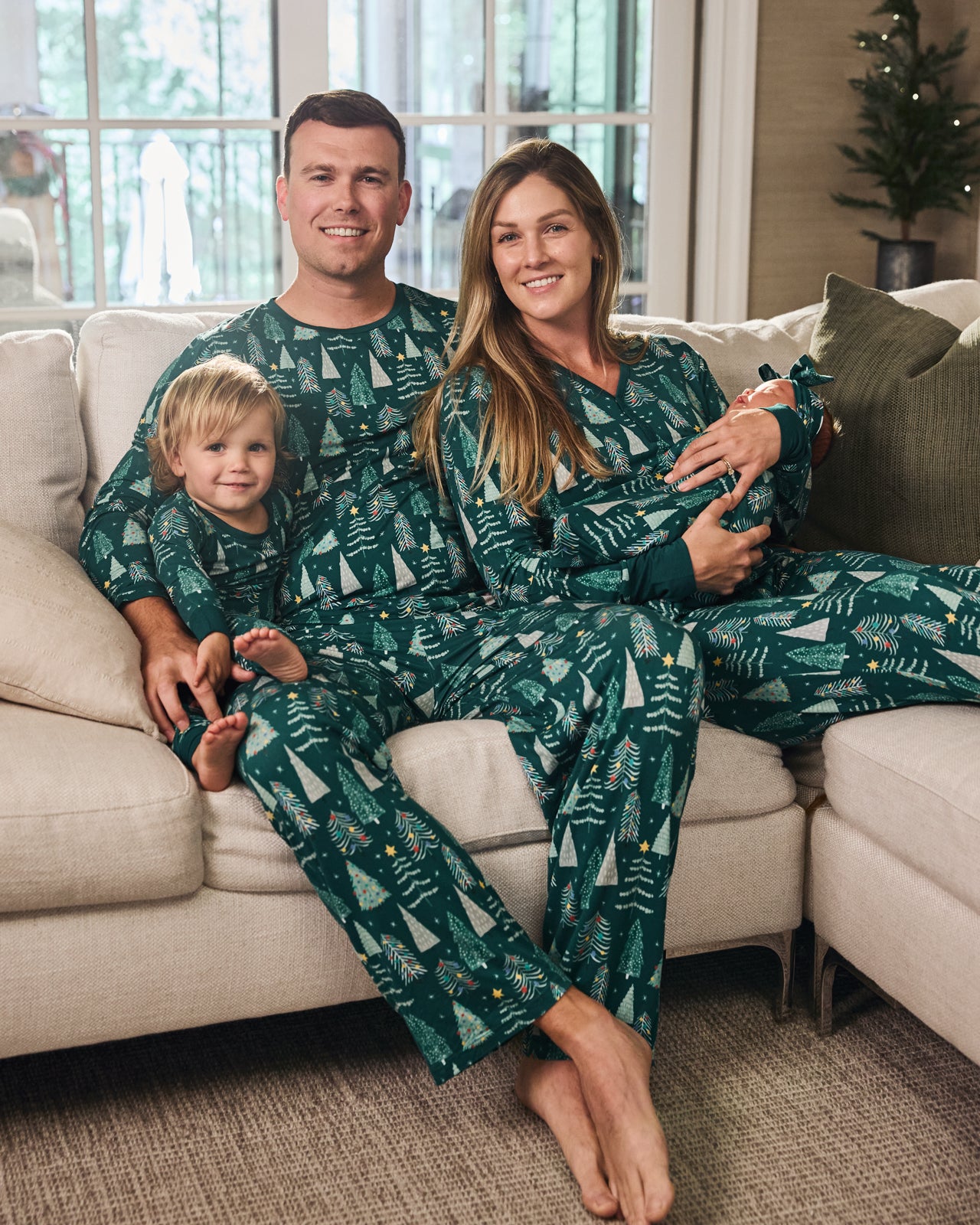Family of four in a living room wearing matching Twinkling Trees pajamas