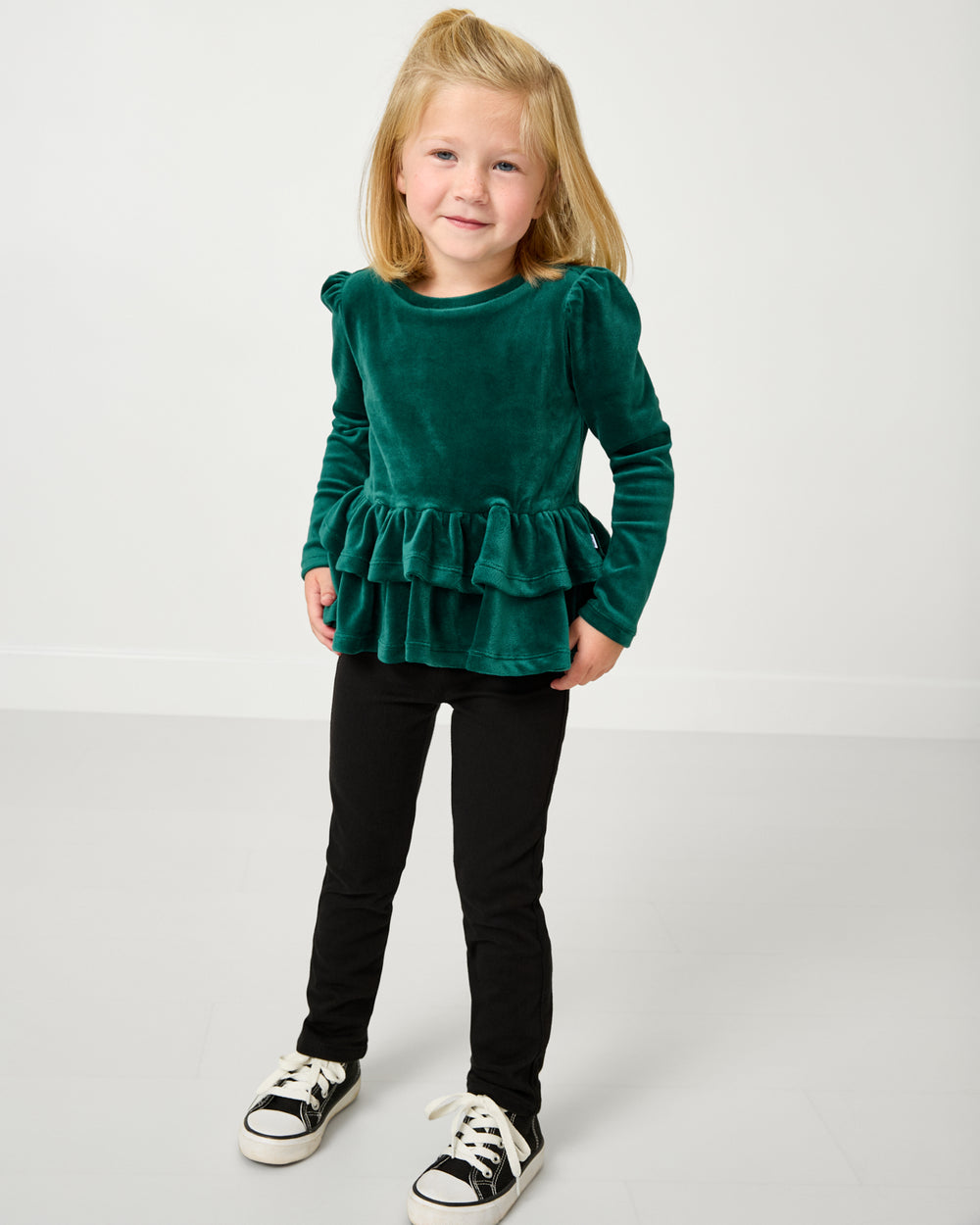 Girl wearing the Emerald Velvet Tiered Peplum Top with black jeggings