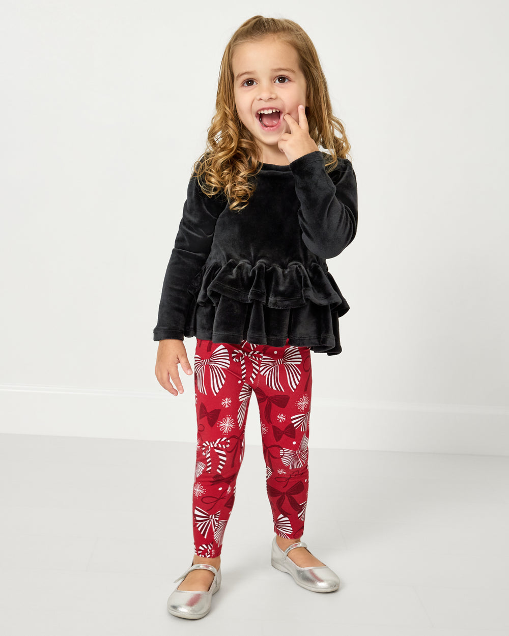 Girl wearing the Black Velvet Tiered Peplum Top with Holiday Bows leggings