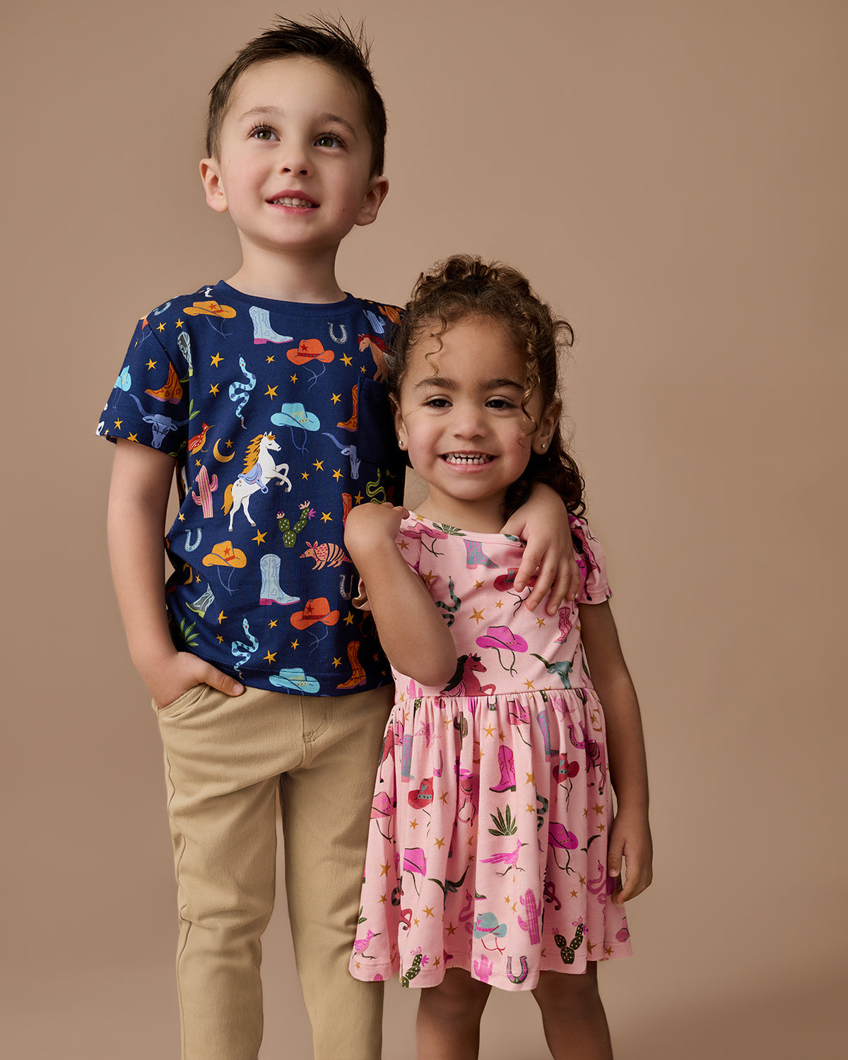 Two kids wearing Rancher Roundup Play styles on a brown background