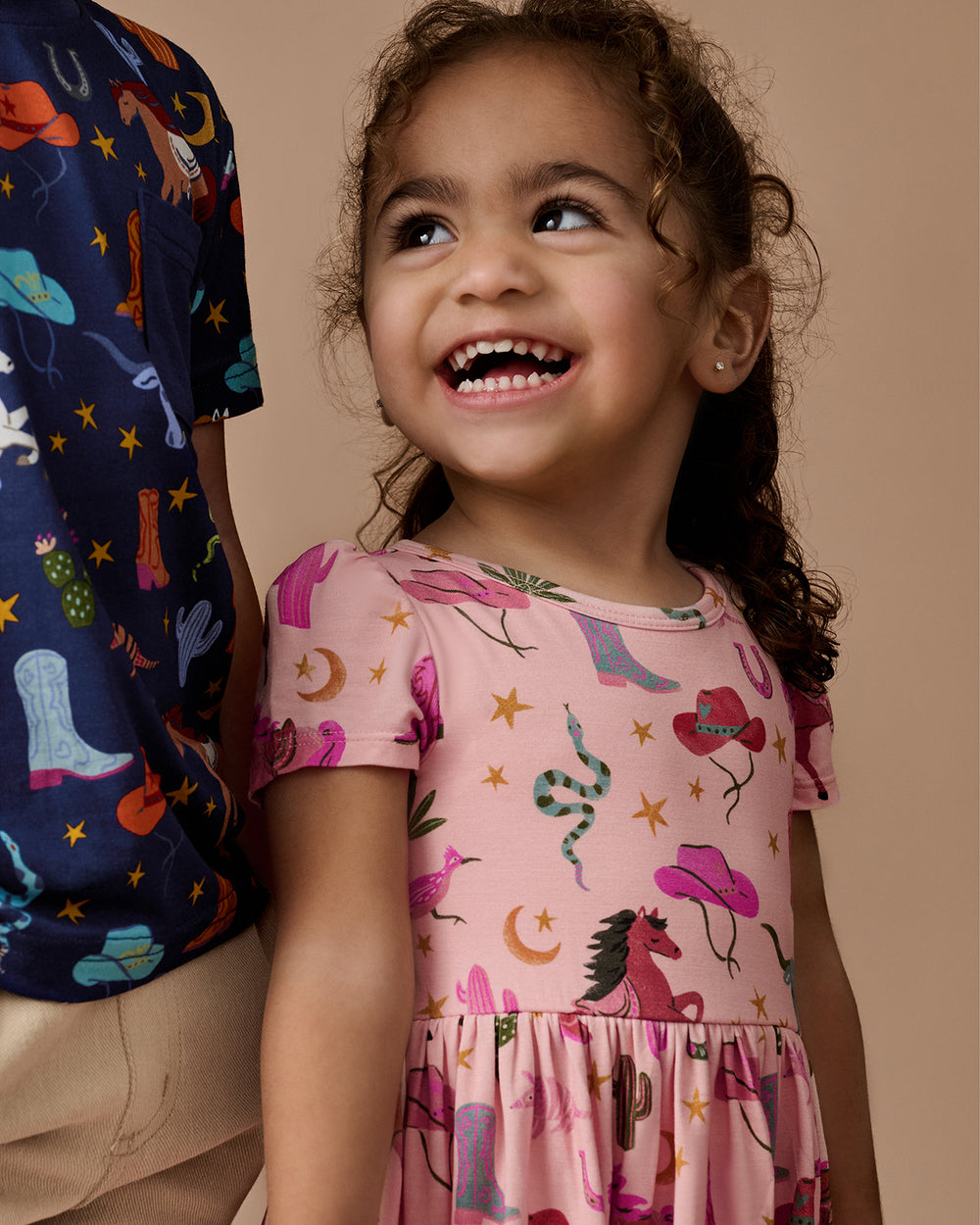 Close up of girl wearing the Pink Rancher Roundup Skater Dress with Bodysuit on a brown background