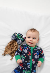Child laying down wearing a Monster Truck Madness Zippy with a Max the Monster Truck Sleepyhead Lovey