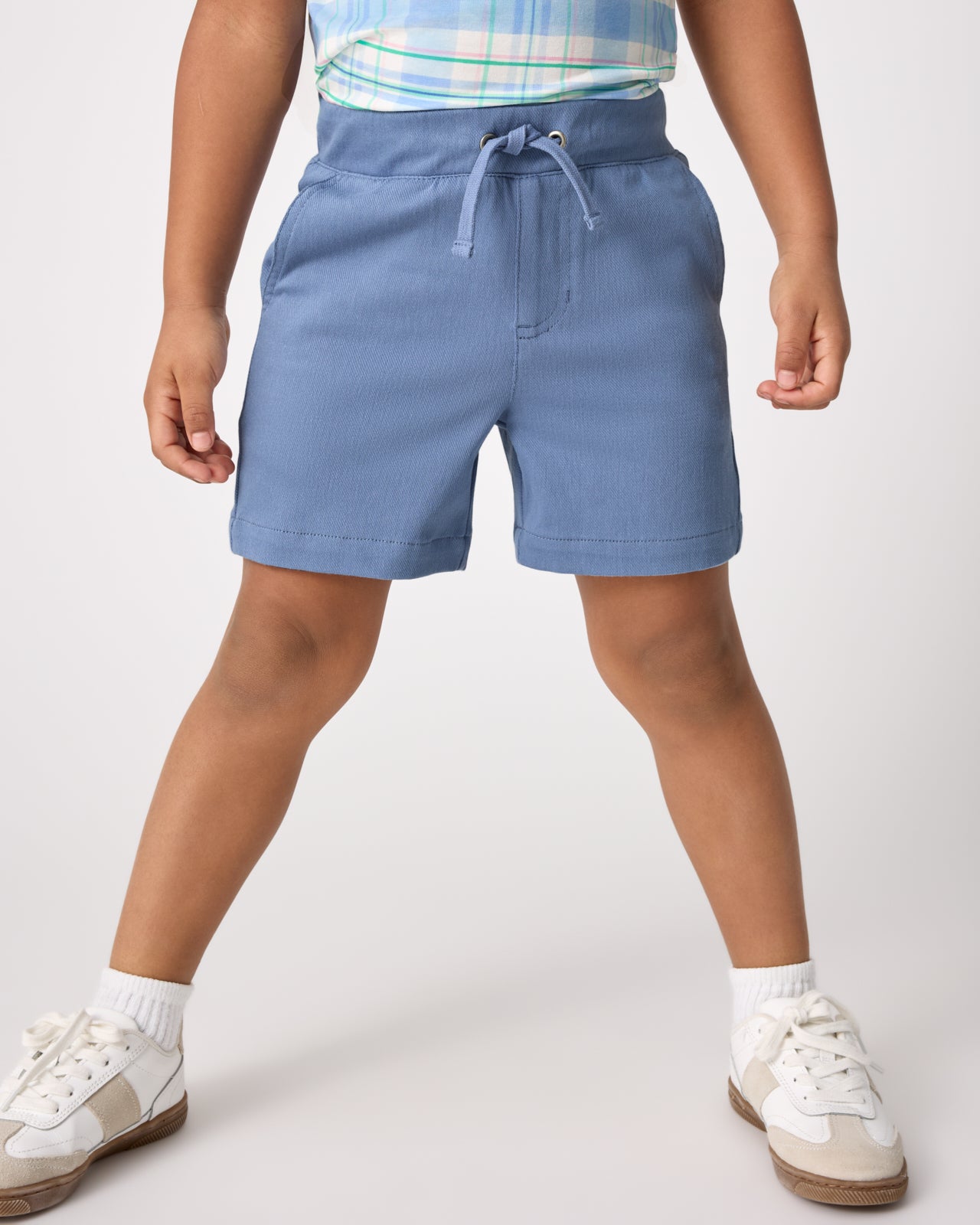 Child wearing the Infinite Blue Chino Shorts with white sneakers 