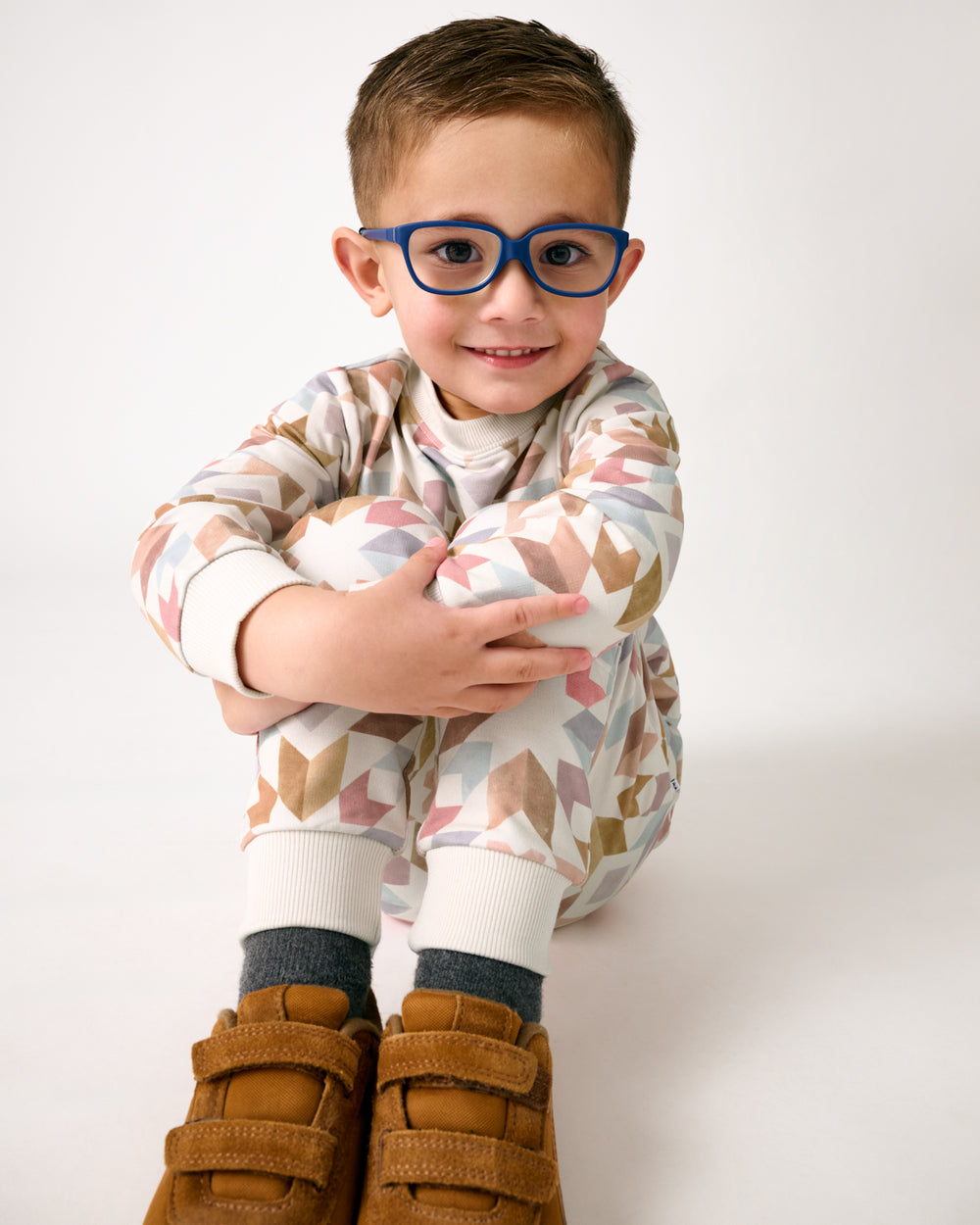 Sitting boy wearing the Kaleidoscope Dreams Jogger with brown suede sneakers