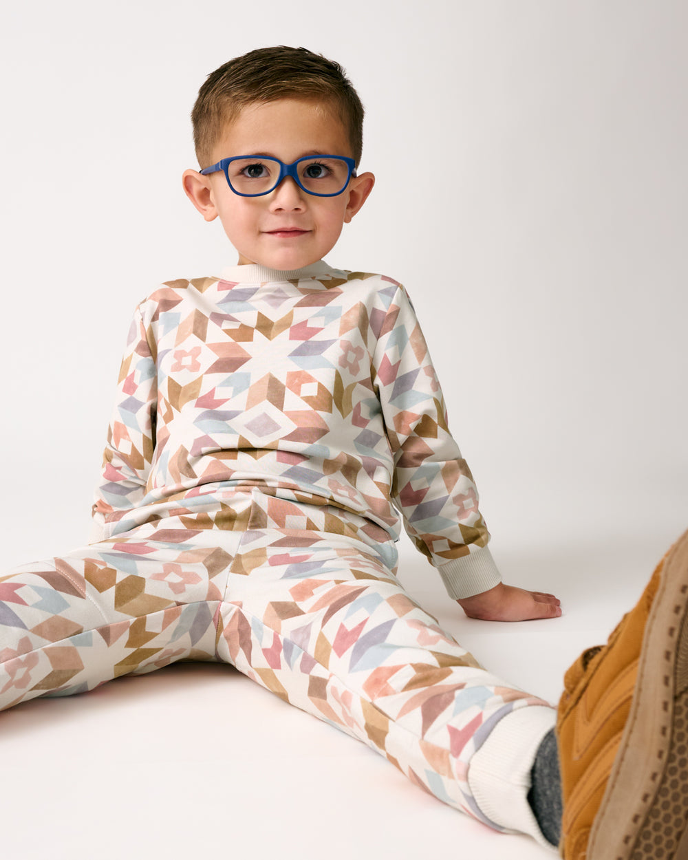 Sitting boy wearing the Kaleidoscope Dreams Jogger and Sweatshirt