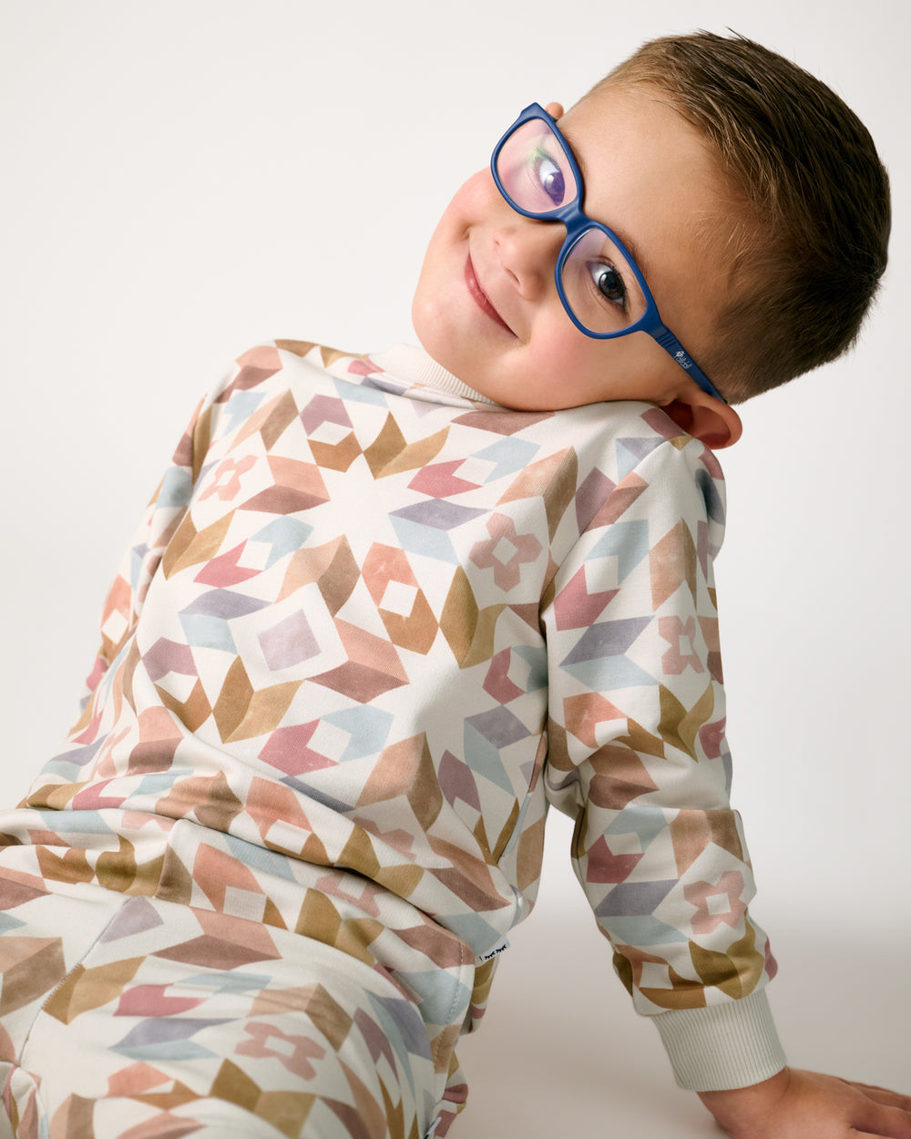 Sitting boy wearing the Kaleidoscope Dreams Crewneck Sweatshirt and Joggers