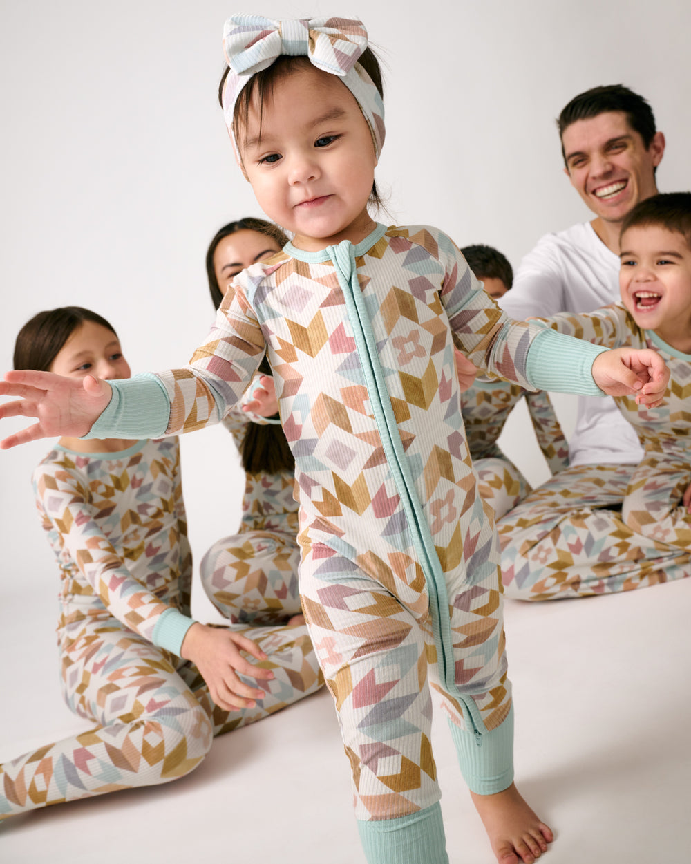 Toddler wearing the Kaleidoscope Dreams Ribbed Zippy with family in the background