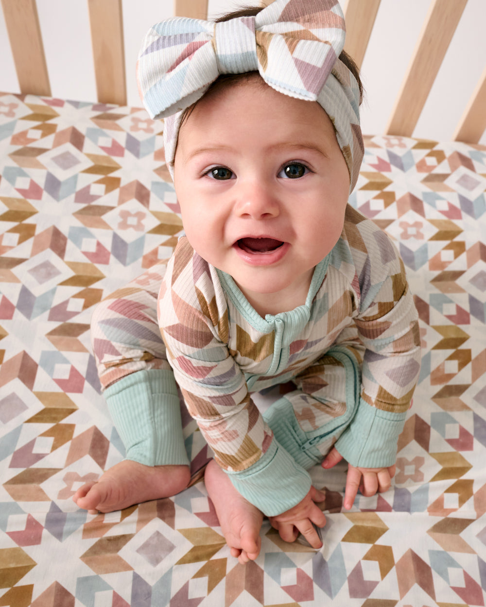 Overhead view of sitting baby wearing the Kaleidoscope Dreams Zippy and matching headband