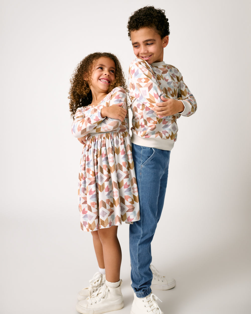 Two kids standing back to back wearing matching Kaleidoscope Dreams play styles