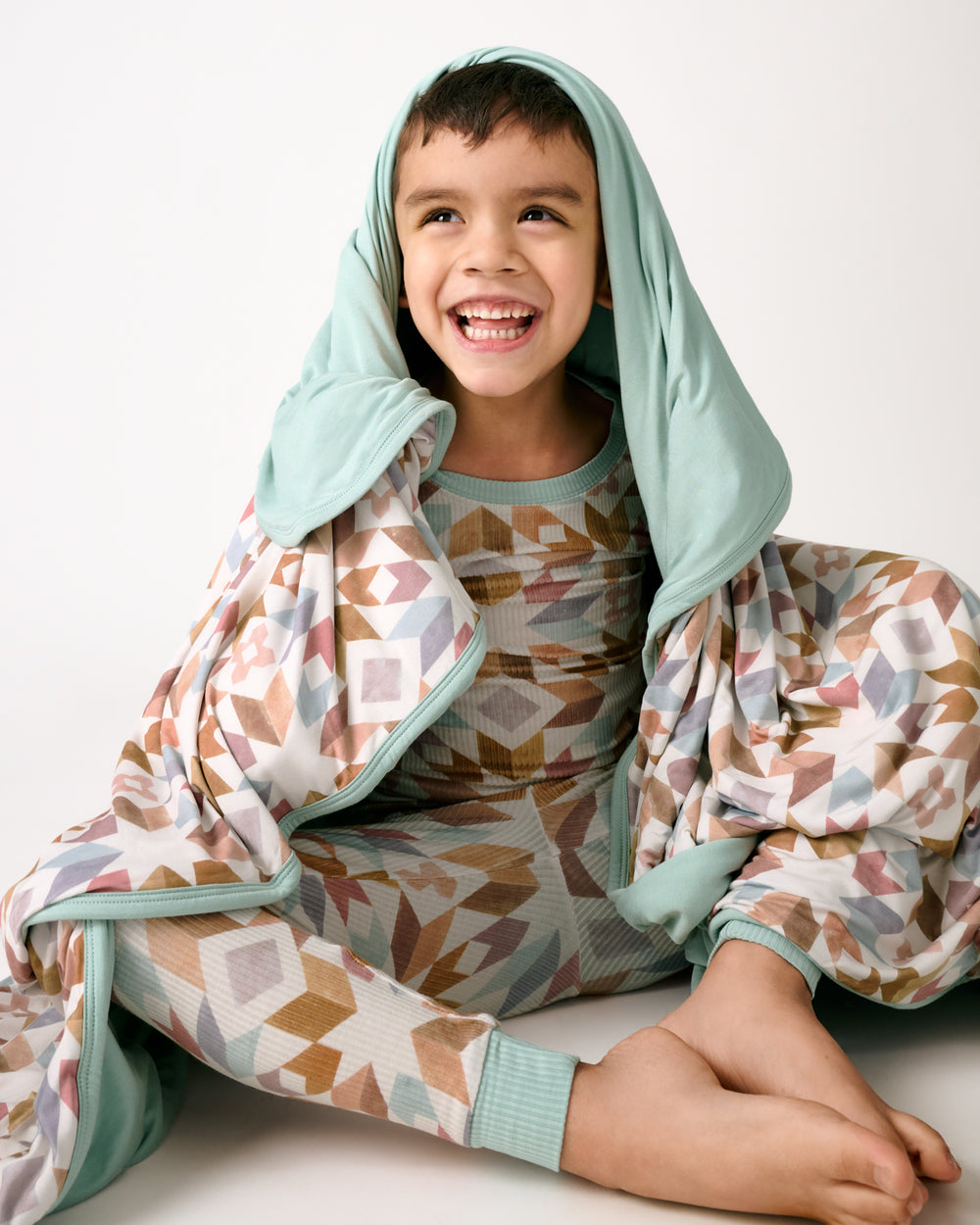 Sitting boy wrapped in the Kaleidoscope Dreams Large Cloud Blanket®