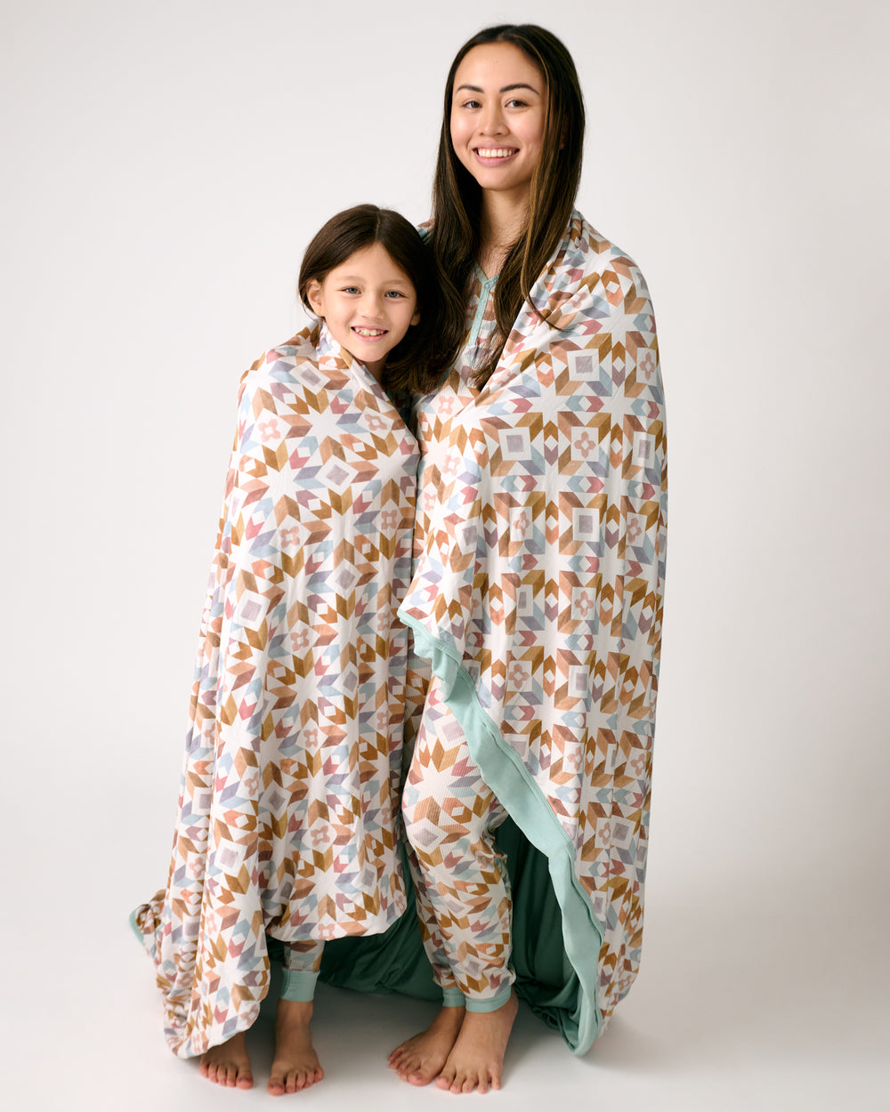 Two people wrapped in the Kaleidoscope Dreams Oversized Cloud Blanket® 