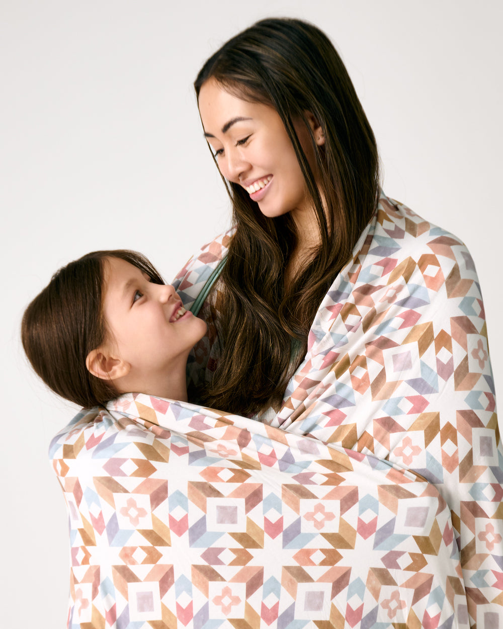 Close up of mother and daughter wrapped in the Kaleidoscope Dreams Oversized Cloud Blanket®